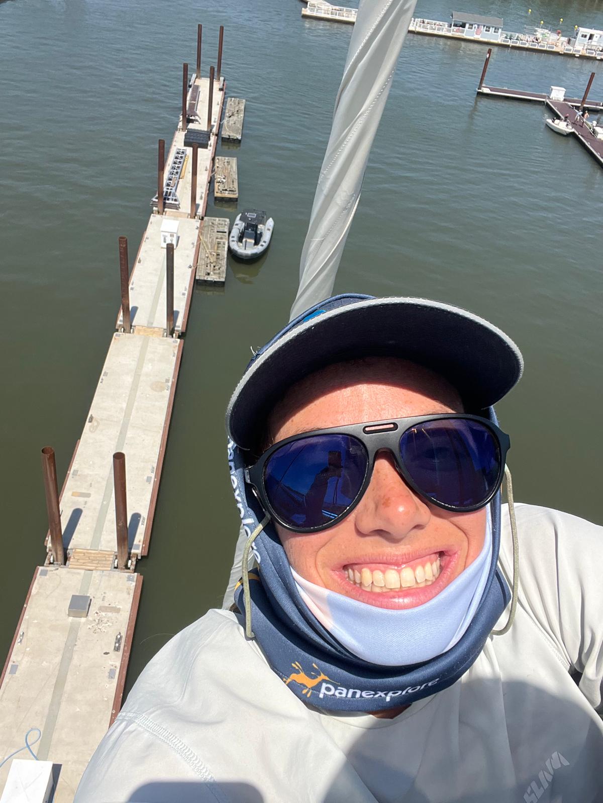 photo of a smiling Shyah, wearing a hat and sunglasses, up the rig in sunshine