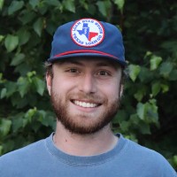 John, wearing a hat and smiling
